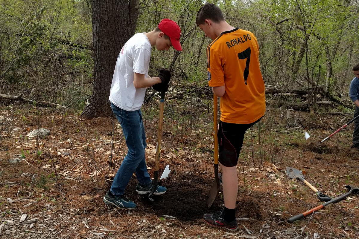 Two volunteers team up to dig a hole. 